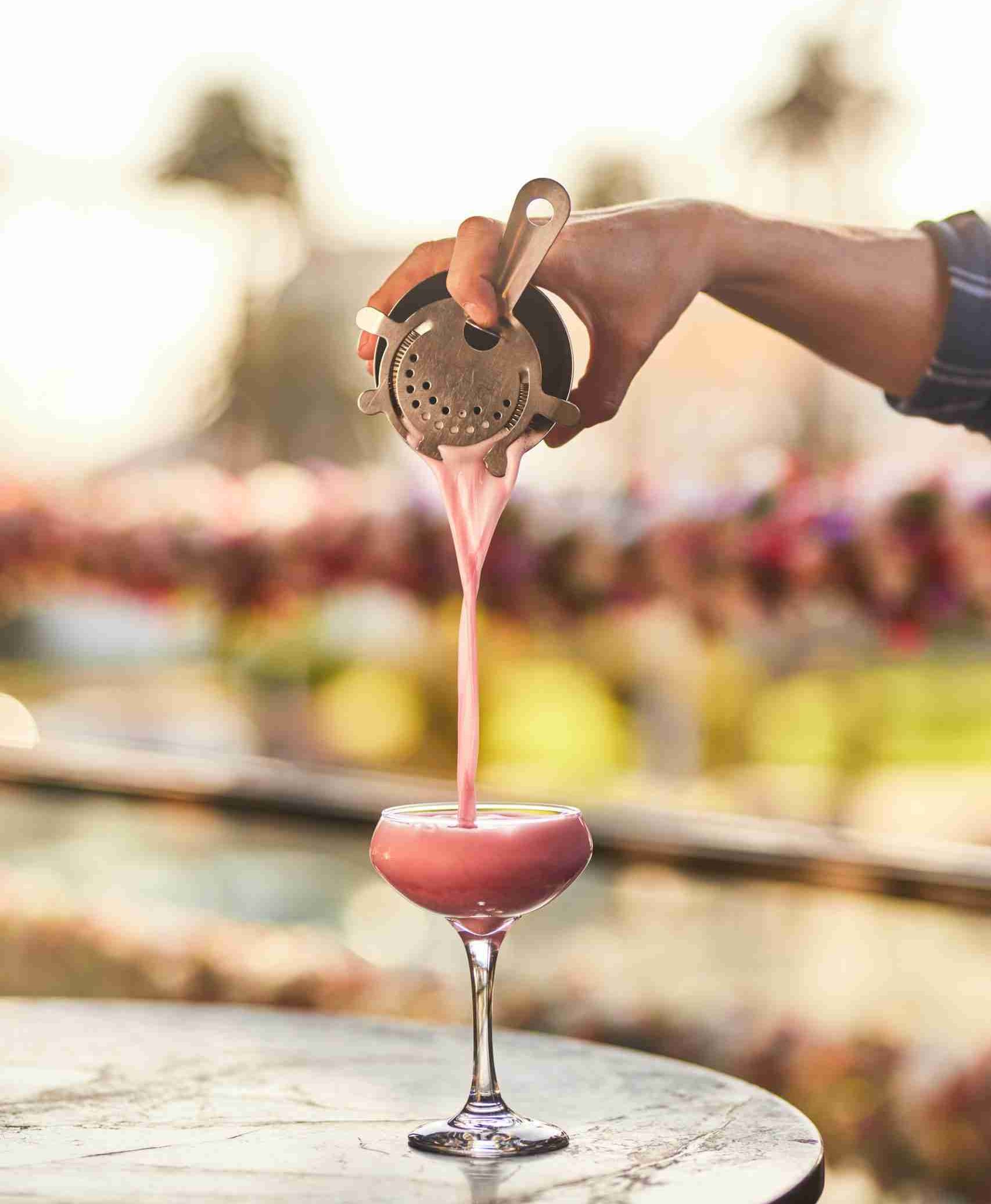 Pink cocktail being poured with iconic St Kilda skyline