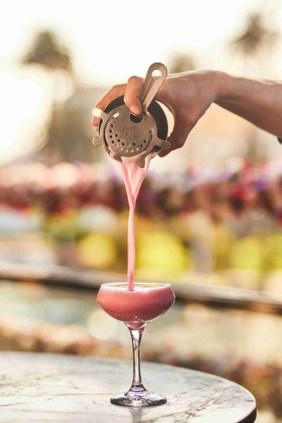 Pink cocktail being poured with iconic St Kilda skyline