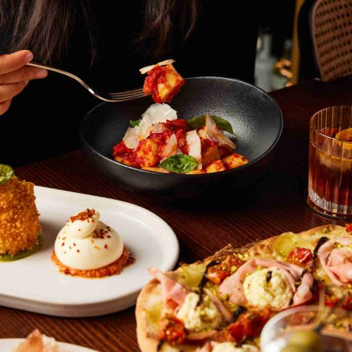 Tomato ricotta gnocchi dish with pinsa and burrata dishes in the background